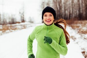 Young woman running in cold, snowy weather.
