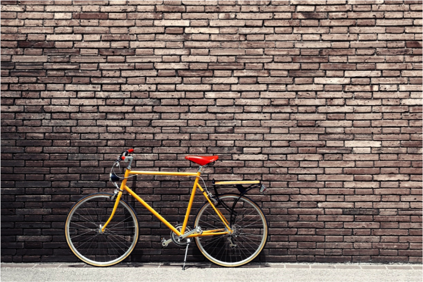 A bicycle in front of a brick wall