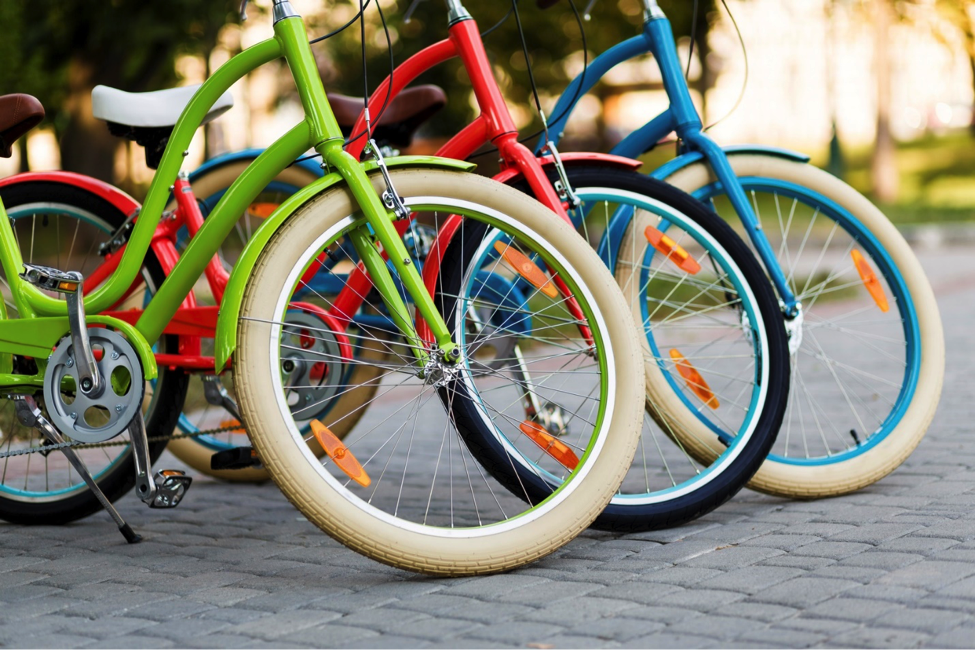 Three colorful bikes parked on a sidewalk. 
