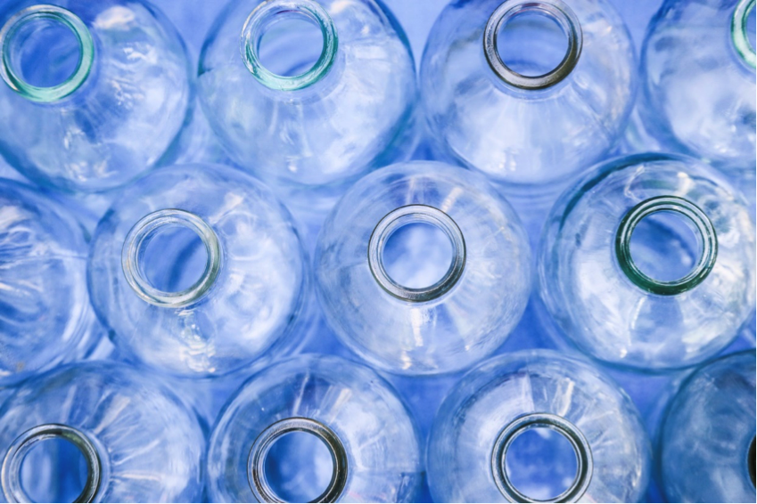 Rows of clear, blue glass bottles from the top.