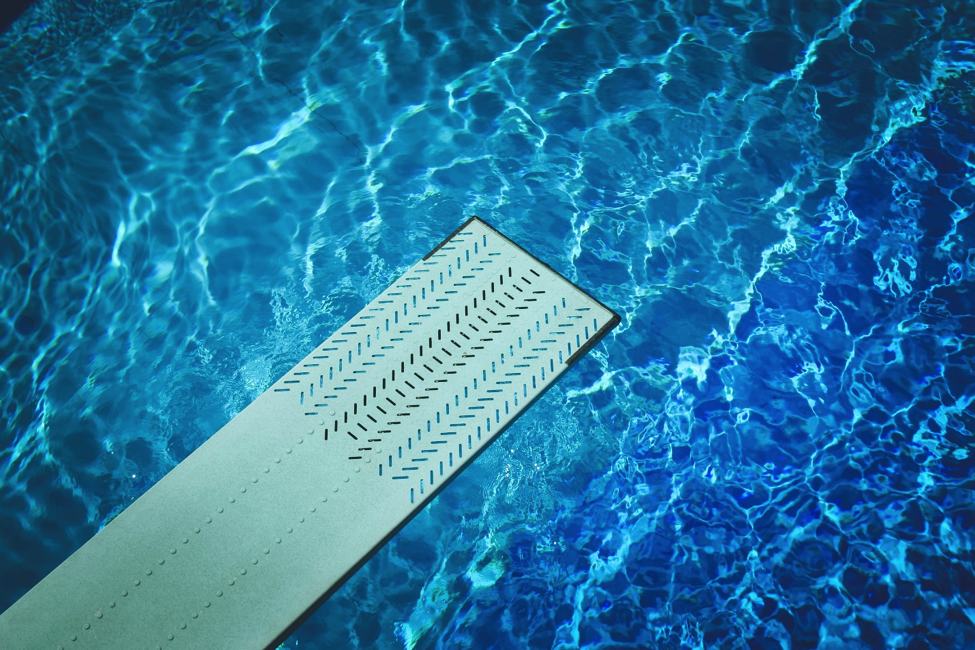 Diving board over clear blue water. 