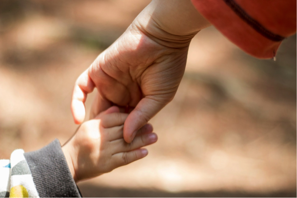 An adult hand holding a child’s hand.