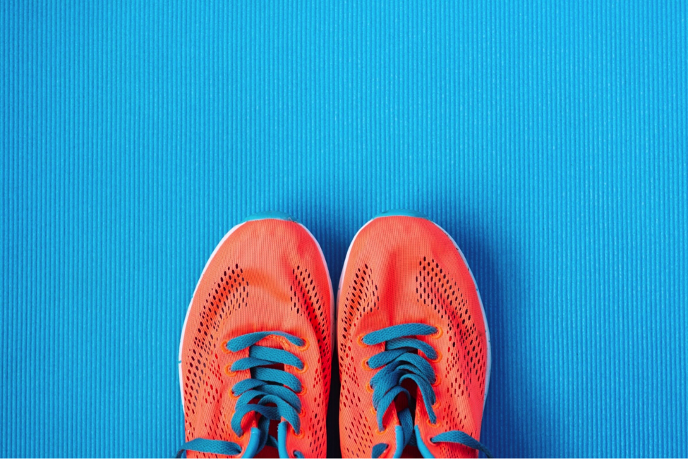 Orange running shoes on a bright blue background.
