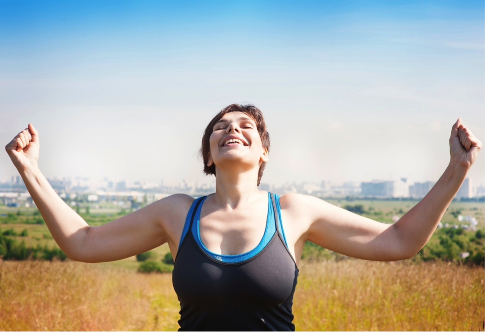 Woman outside raising arms to show happiness at learning how to achieve realistic weight loss goals