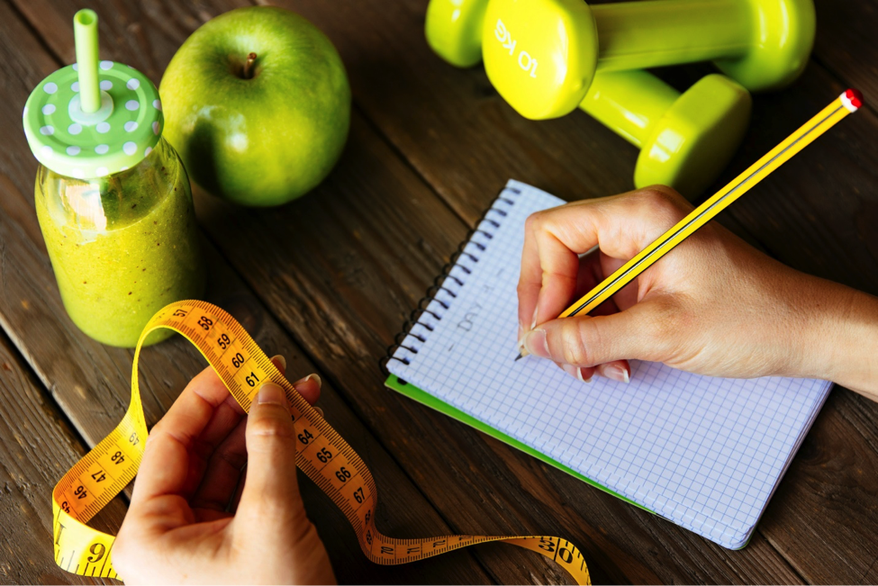 Person holding measuring tape and tracking realistic weight loss goals