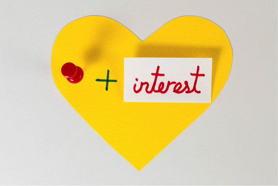 Paper heart with a pin, plus size, and the word ‘interest’.