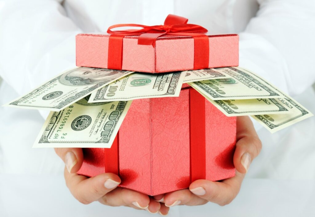 Dollar bills coming out of red Christmas gift