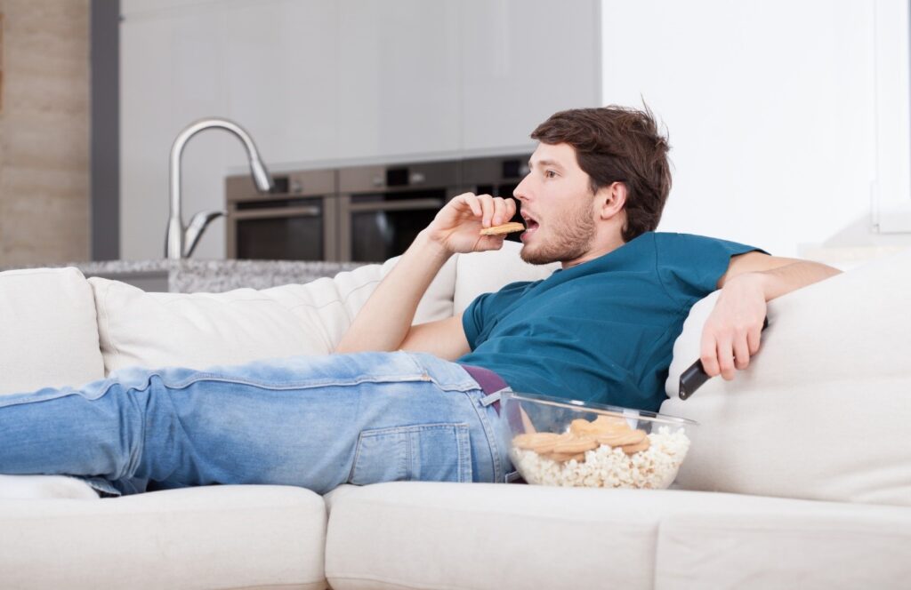 Man overeating while sitting on couch