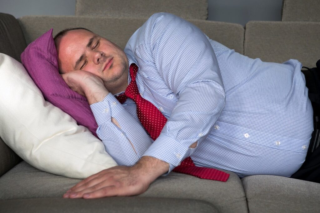 Man sleeping on couch after overeating