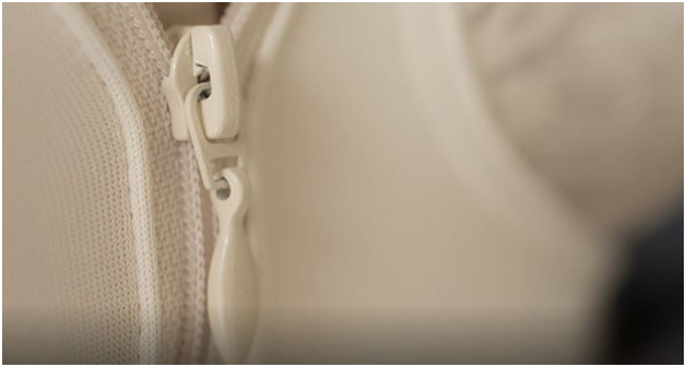 A close-up of the zipper of a beige shapewear garment