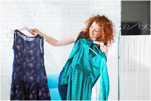 Woman holding up two different dresses as she shops