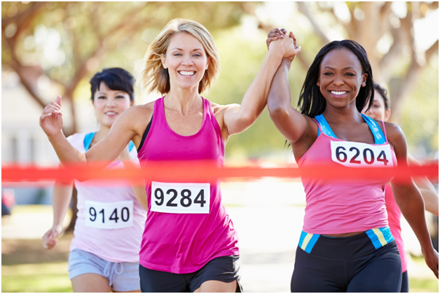 Women holding hands and crossing finish line together