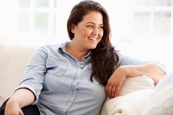 Plus size woman with a healthy body image sitting on the couch and smiling