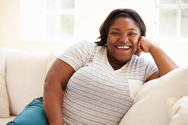 Overweight woman smiling and sitting on a couch