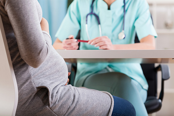 Pregnant woman sitting and talking to a nurse 