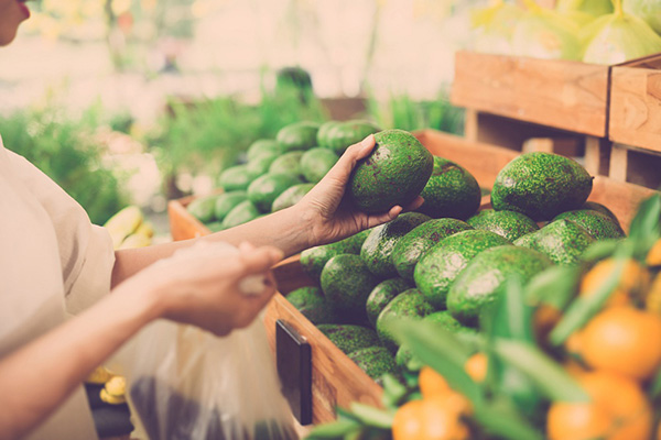 Woman choosing an organic avocado while grocery shopping