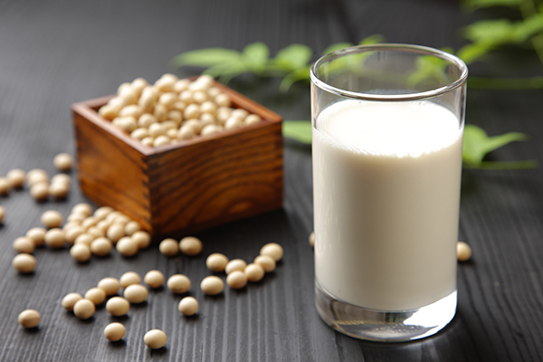Glass of soy milk near a wooden box of soy beans for low-carb cooking