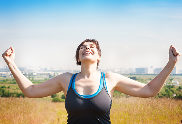 Woman raising arms and happily looking towards the sky.