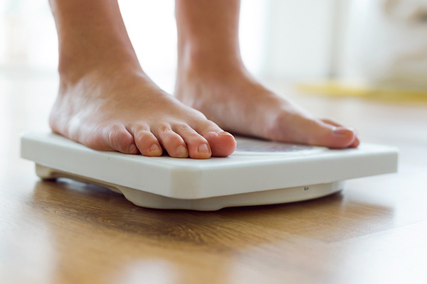 Close up of person standing on a white weight scale.