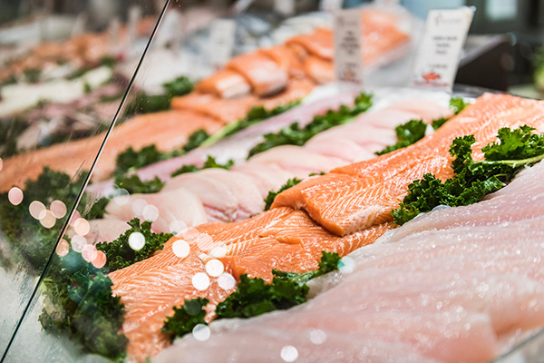 Salmon and other fish laid out on ice at supermarket.