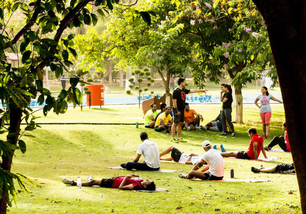 Adults sitting on mats in a park to achieve a healthy spring bucket list.