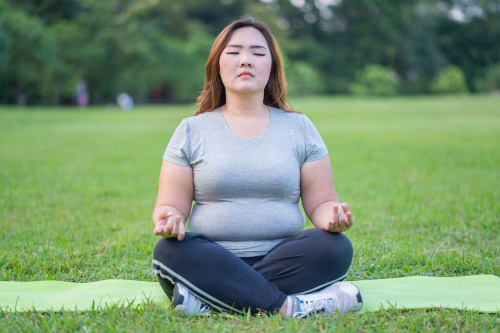 Young woman sitting in the grass performing meditation for a healthy spring.