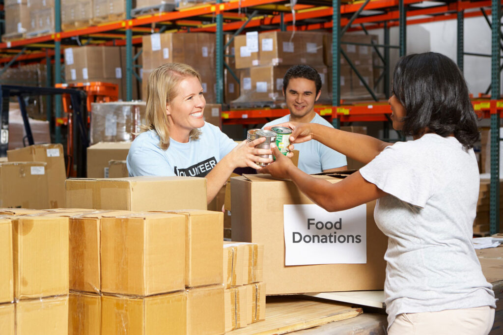 Woman handing food donations to another woman at a food drive.