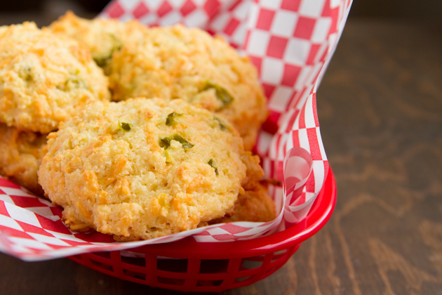 Red plastic basket and checkered paper underneath a low-carb Easter recipe, “Cheddar” Drop Biscuits.