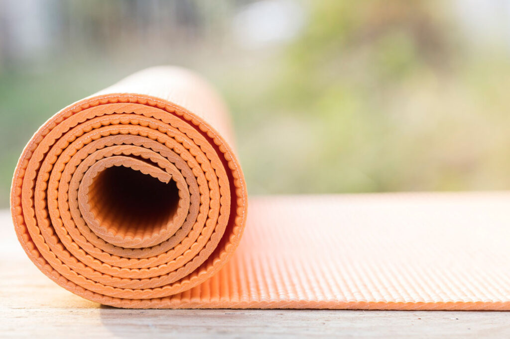 Close up of orange yoga mat rolled up at the end.