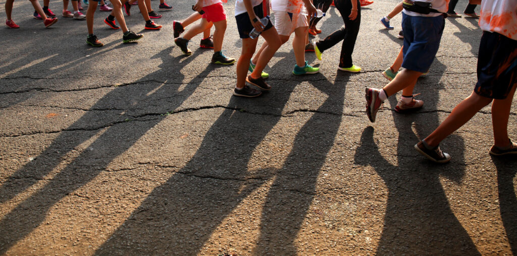 Close up of people walking and their shadows against the pavement.