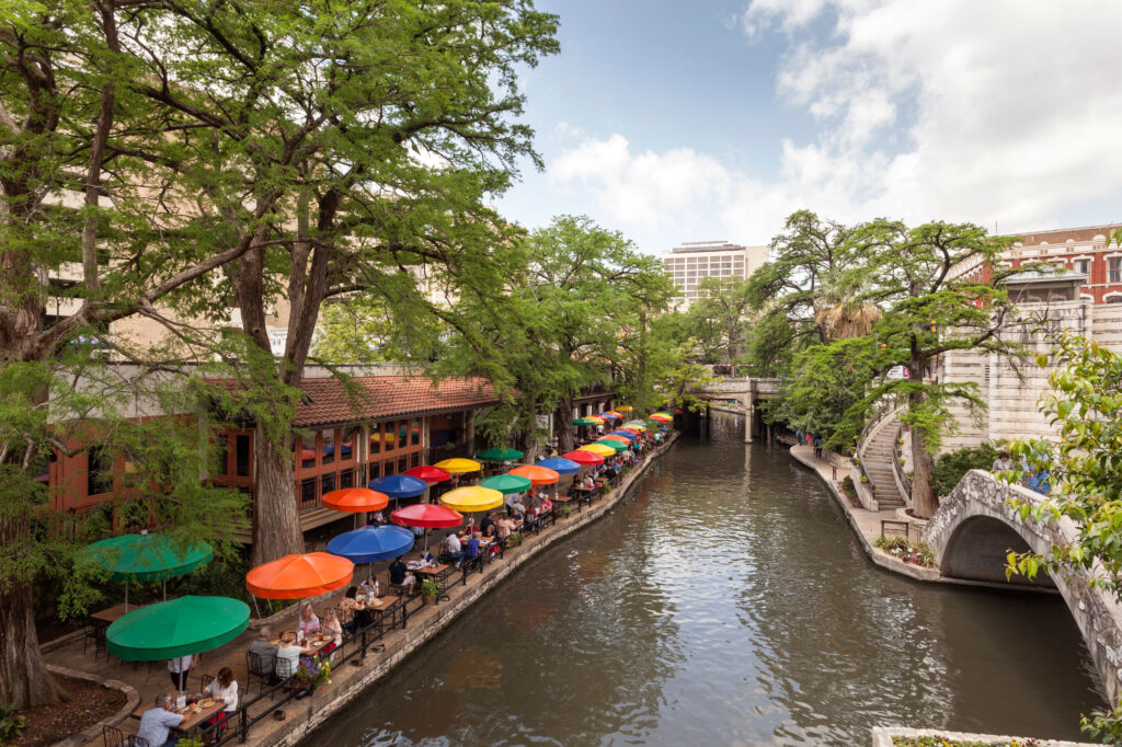 View of the restaurants and colorful umbrellas that line the water at the San Antonio River Walk.