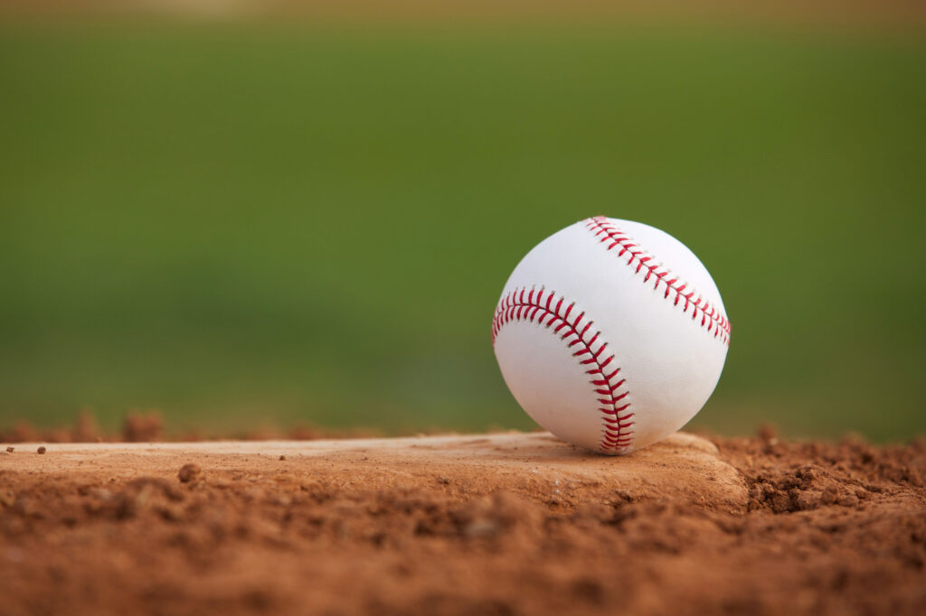 Close up of clean baseball sitting on a dirty base.