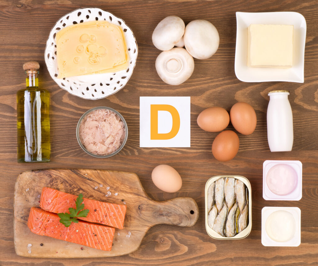 A letter D is surrounded by different kinds of food that contain vitamin D health benefits.