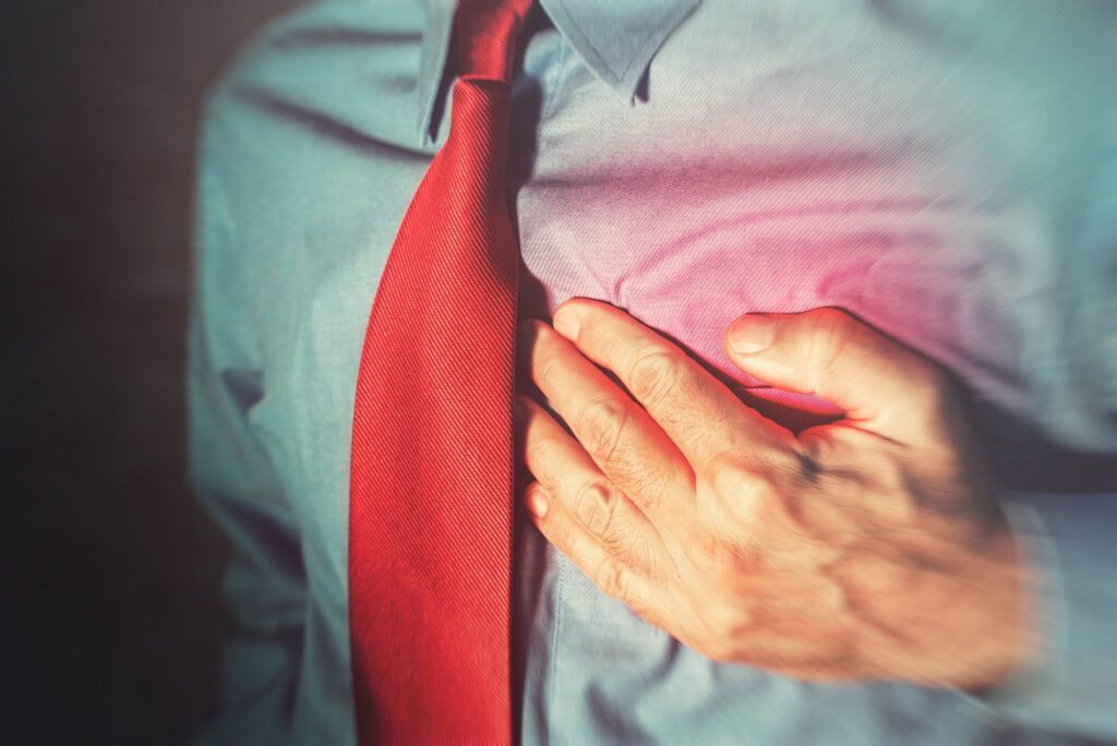 up of man holding chest around red mark to represent pain.