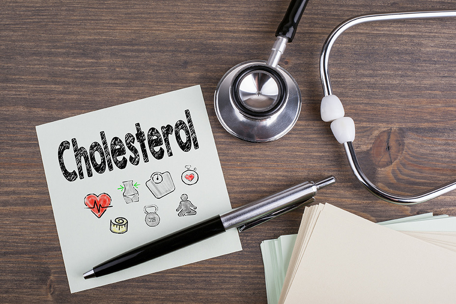 Sign reading ‘Cholesterol’ with pen, paper, and stethoscope laid out nearby.