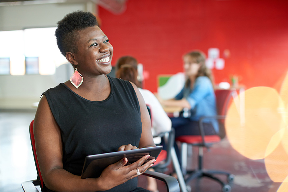 Woman smiling and holding tablet while working.