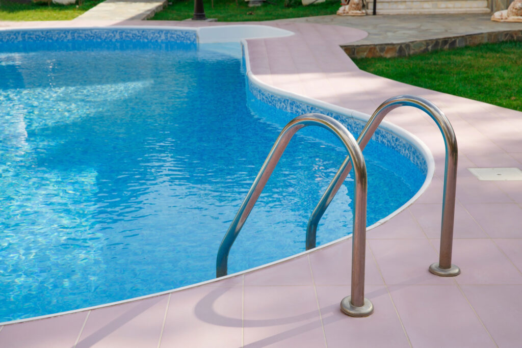 One end of a blue pool with silver hand rails.