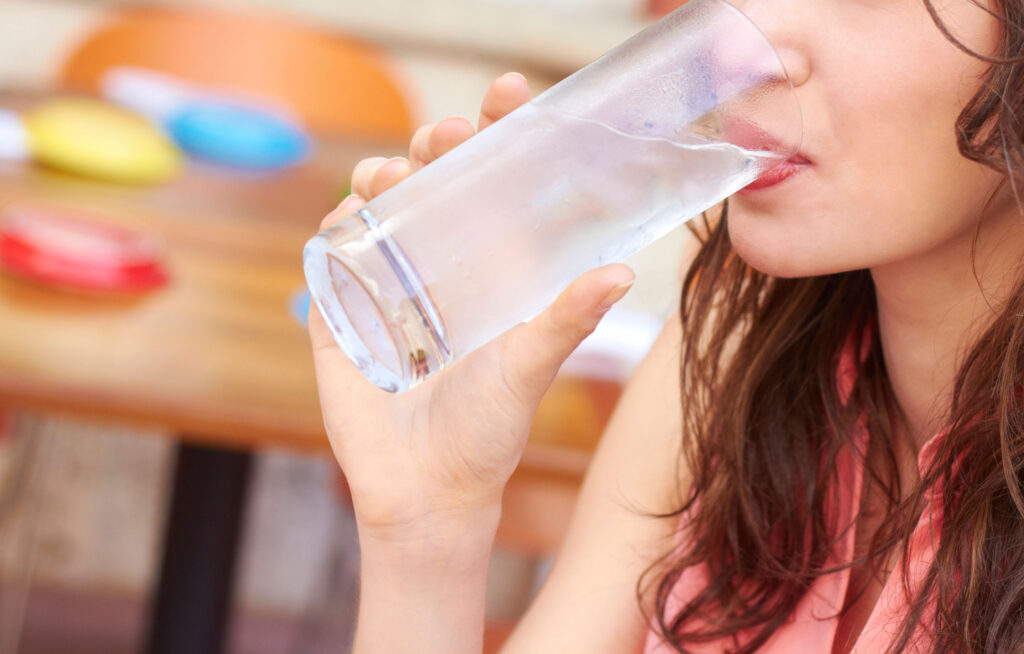 Woman drinking a glass of water in order to keep hydrated.
