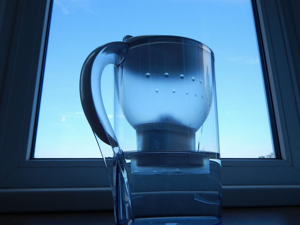 Water filter pitcher in front of window with blue hue.