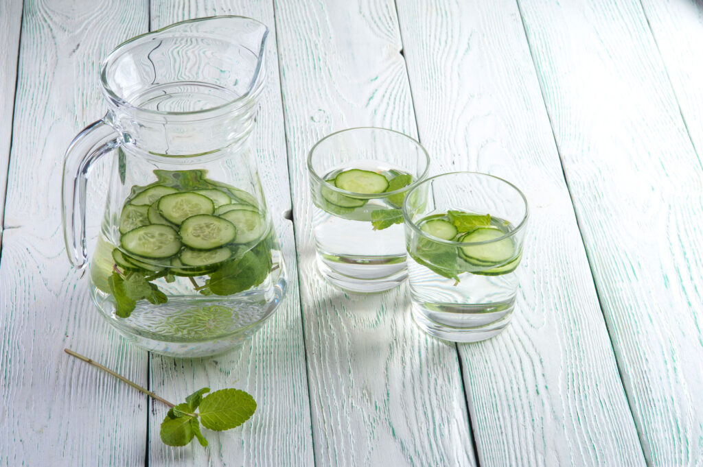 Pitcher and glasses with water and cucumbers.