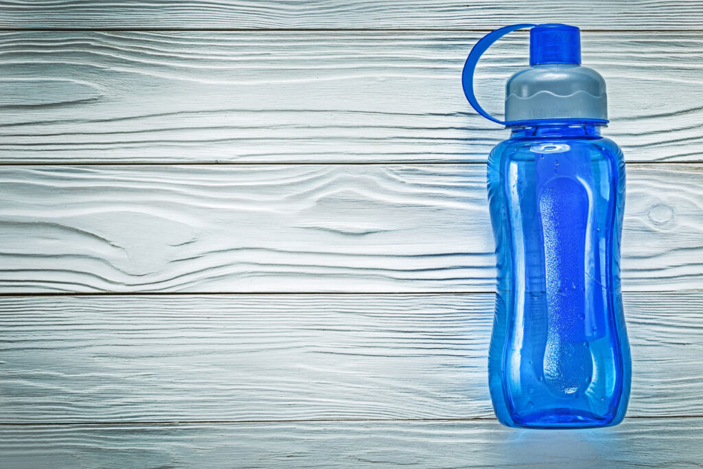 Blue reusable water bottle on white wooden background.