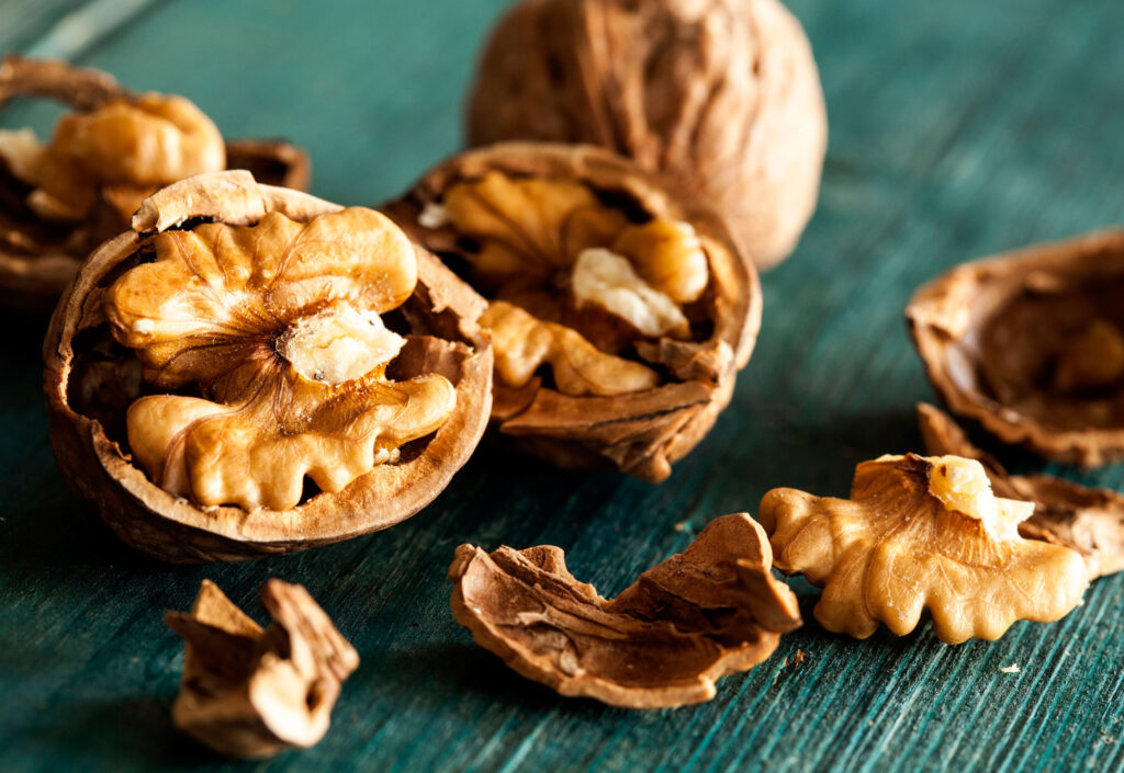 Broken walnut pieces and halves on a blue wooden table.