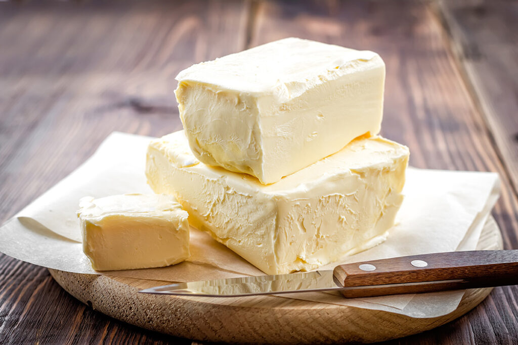 Butter and knife sitting on parchment on top of a wooden table.