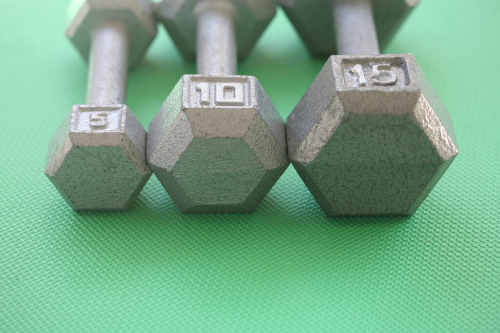 Three different sized weights on green mat.