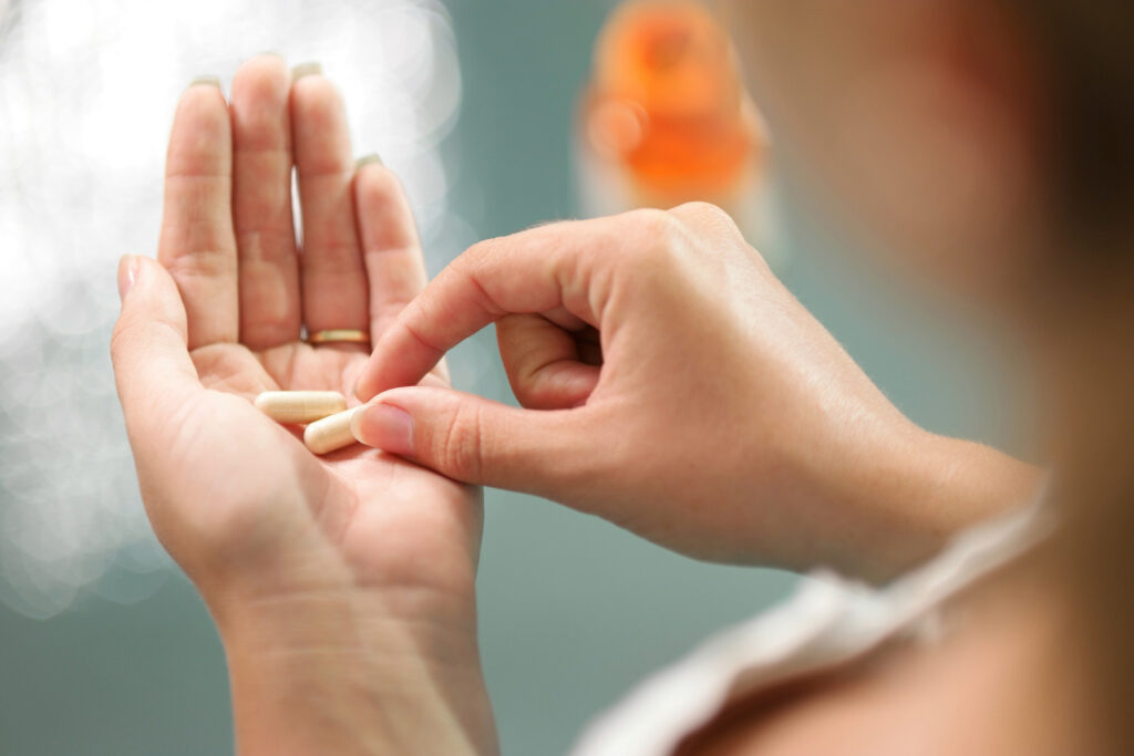 Close up of person picking up a vitamin from her other hand.