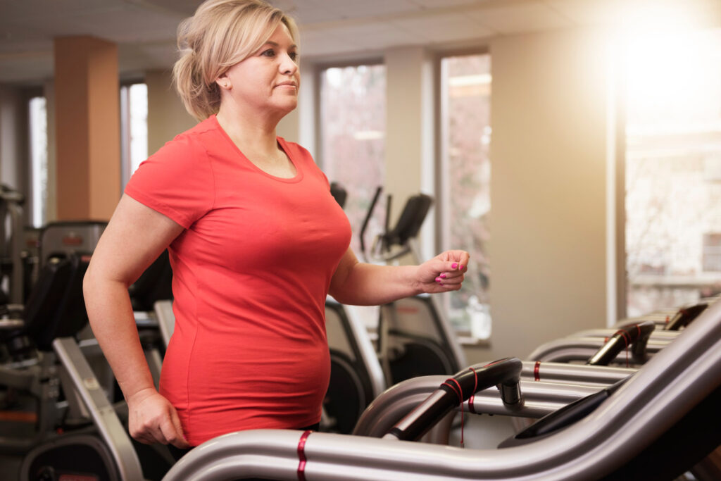 Woman walking on a treadmill in a gym while recovering from surgery.