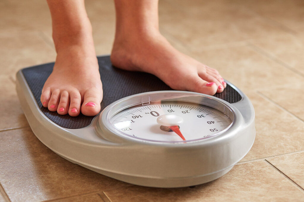 Fat man measuring his weight on a scale. top view.bare feet of an overweight  man