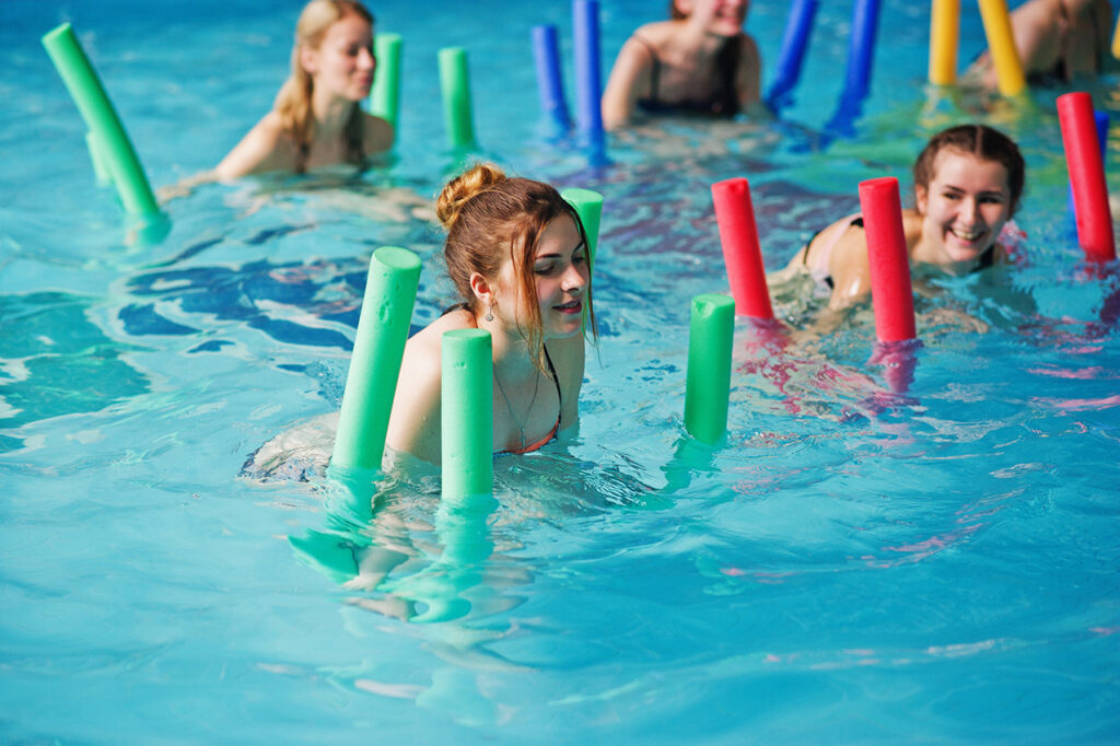 Women using pool noodles for aerobic exercise to learn how to reduce abdominal fat.