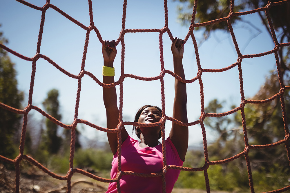 A woman climbing up a rope net to represent San Antonio fitness options.